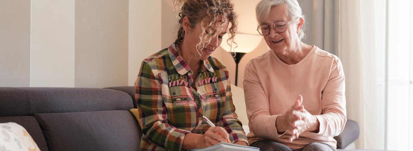 caregiver writing something for older woman at home