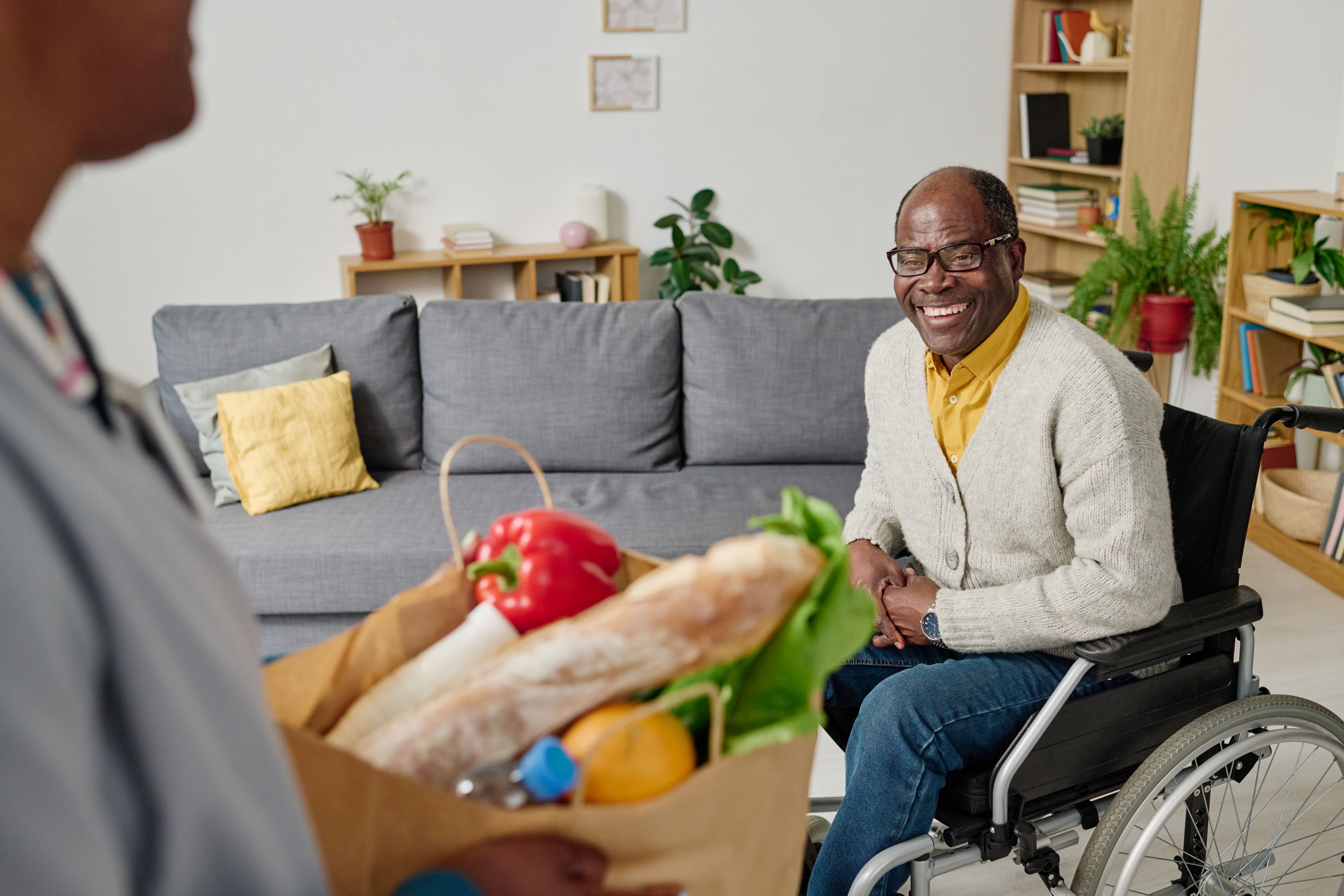 older man in wheel chair receiving bag of groceries