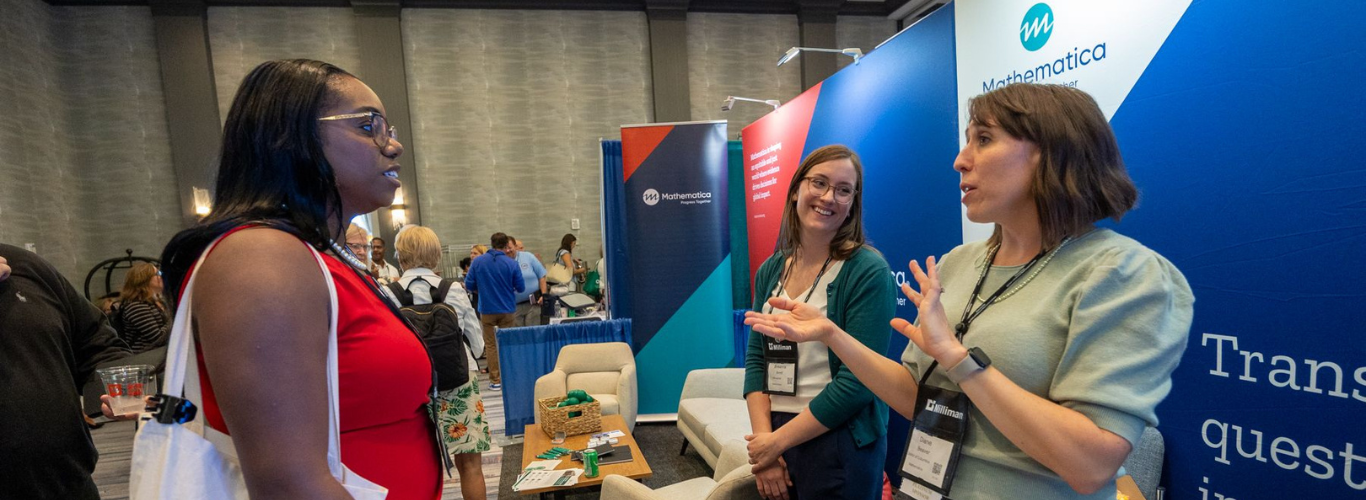 Woman speaks to HCBS conference attendee in the exhibit hall